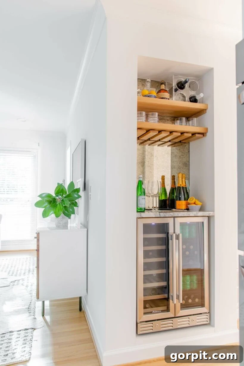 Chic mini built-in bar in a small nook with an antique glass mirrored backsplash and a beverage fridge