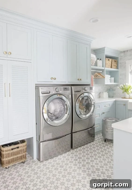 A very pale blue gray laundry room with cabinets, shelves, and a stainless steel washer and dryer. 