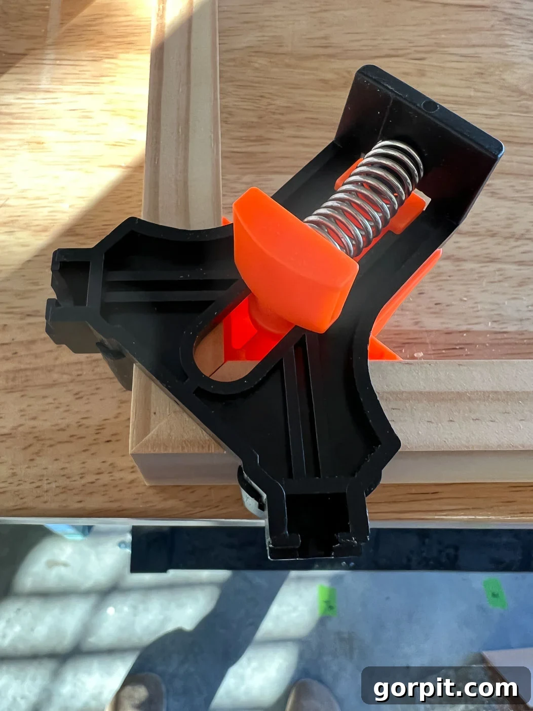 Mitered corners of a DIY canvas frame held securely by corner clamps during the gluing process