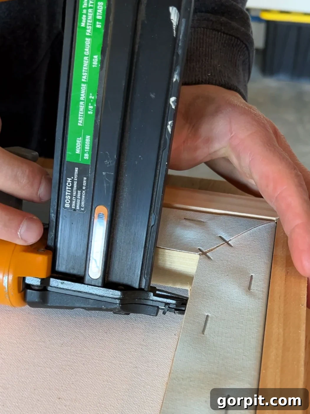 Attaching canvas to a flush mount DIY frame using a nail gun, nailing from the canvas side to hide fasteners