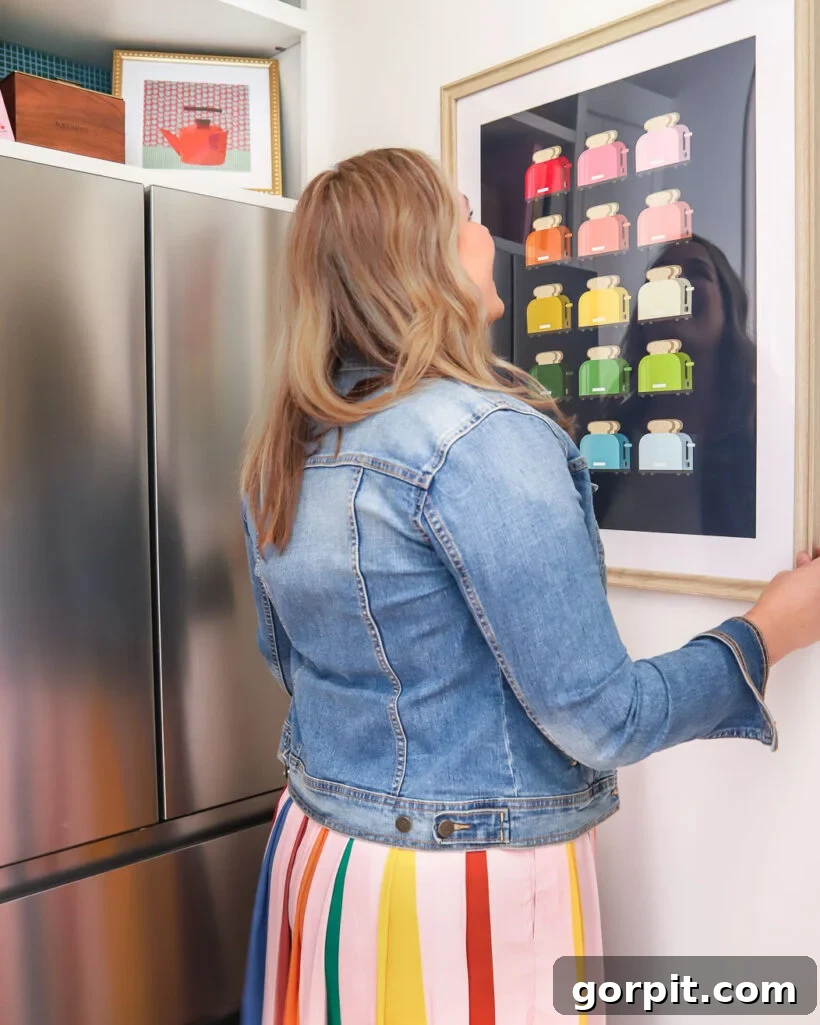 Designer Tasha Agruso hanging colorful artwork in the newly completed butler's pantry.