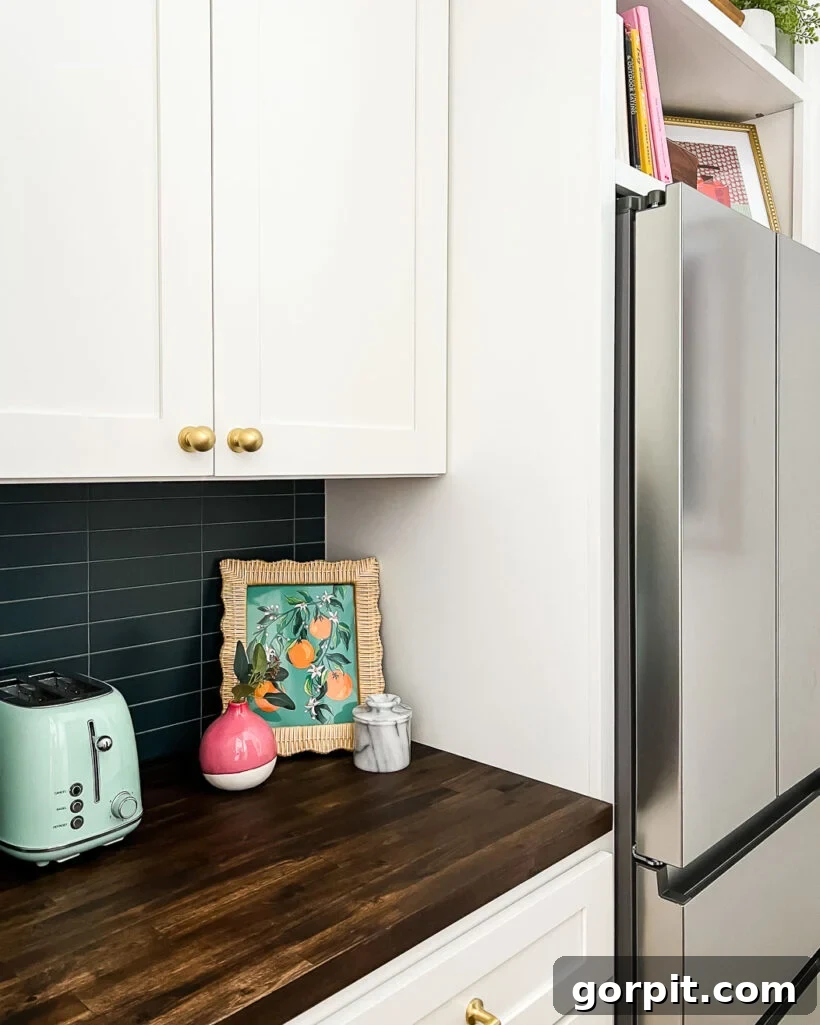 Colorful butler's pantry featuring navy blue tile, white cabinetry, open shelving with cookbooks and a toaster, and vibrant art.