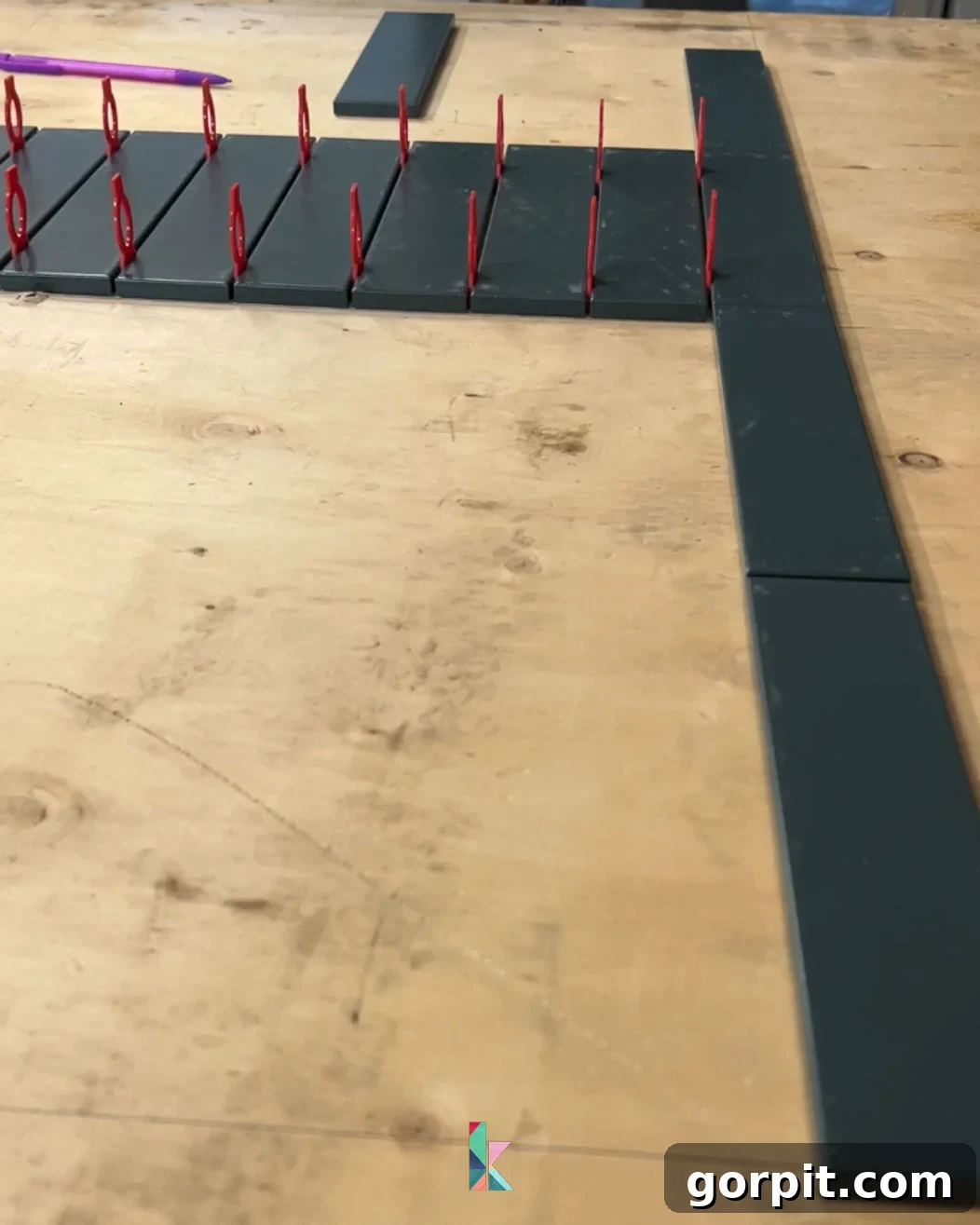Dry laying tile on a flat surface to meticulously check the layout and spacing before commencing backsplash installation, ensuring a balanced and professional finish.