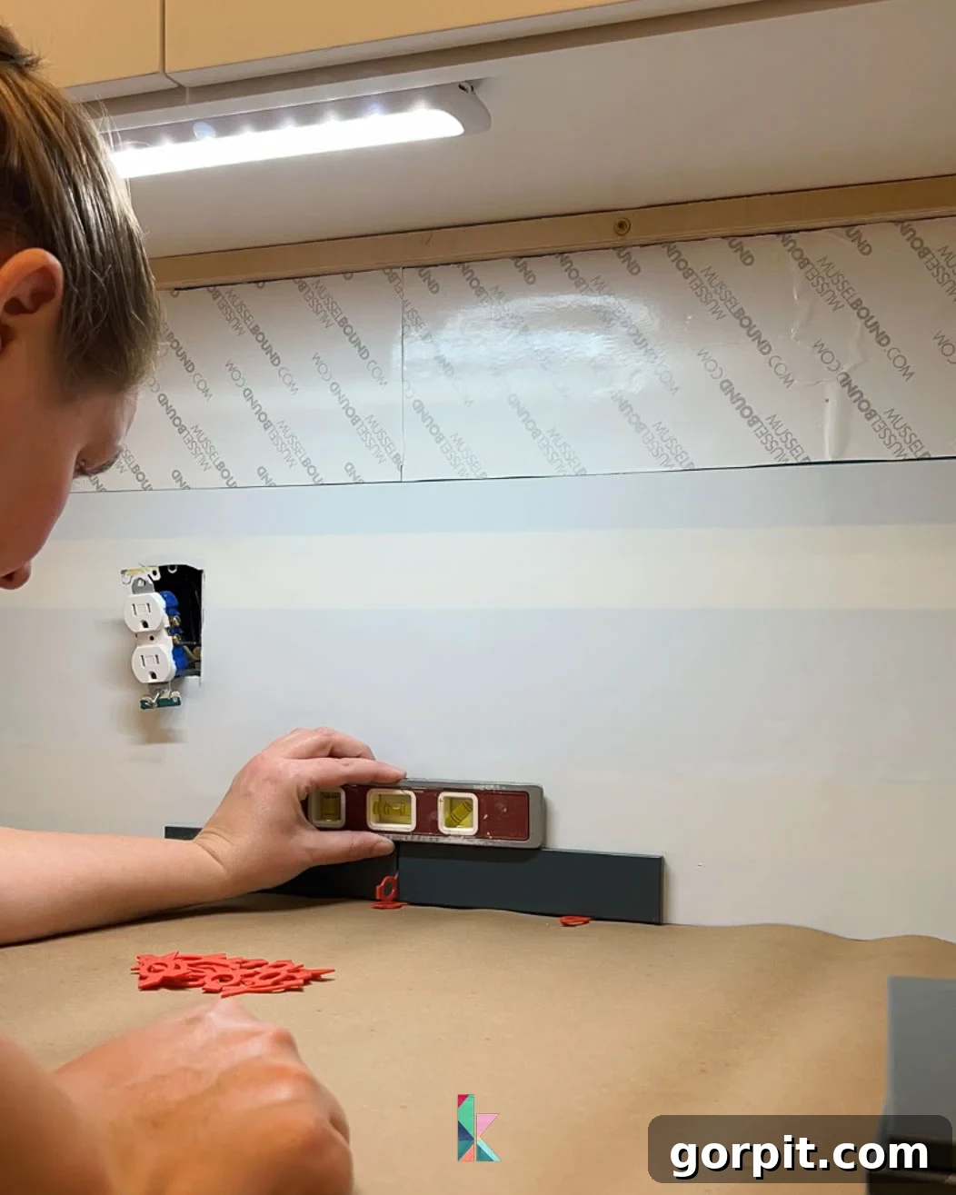 Installing the first row of a tile backsplash, with careful attention to spacing and ensuring a perfectly level foundation for the entire tiled area.