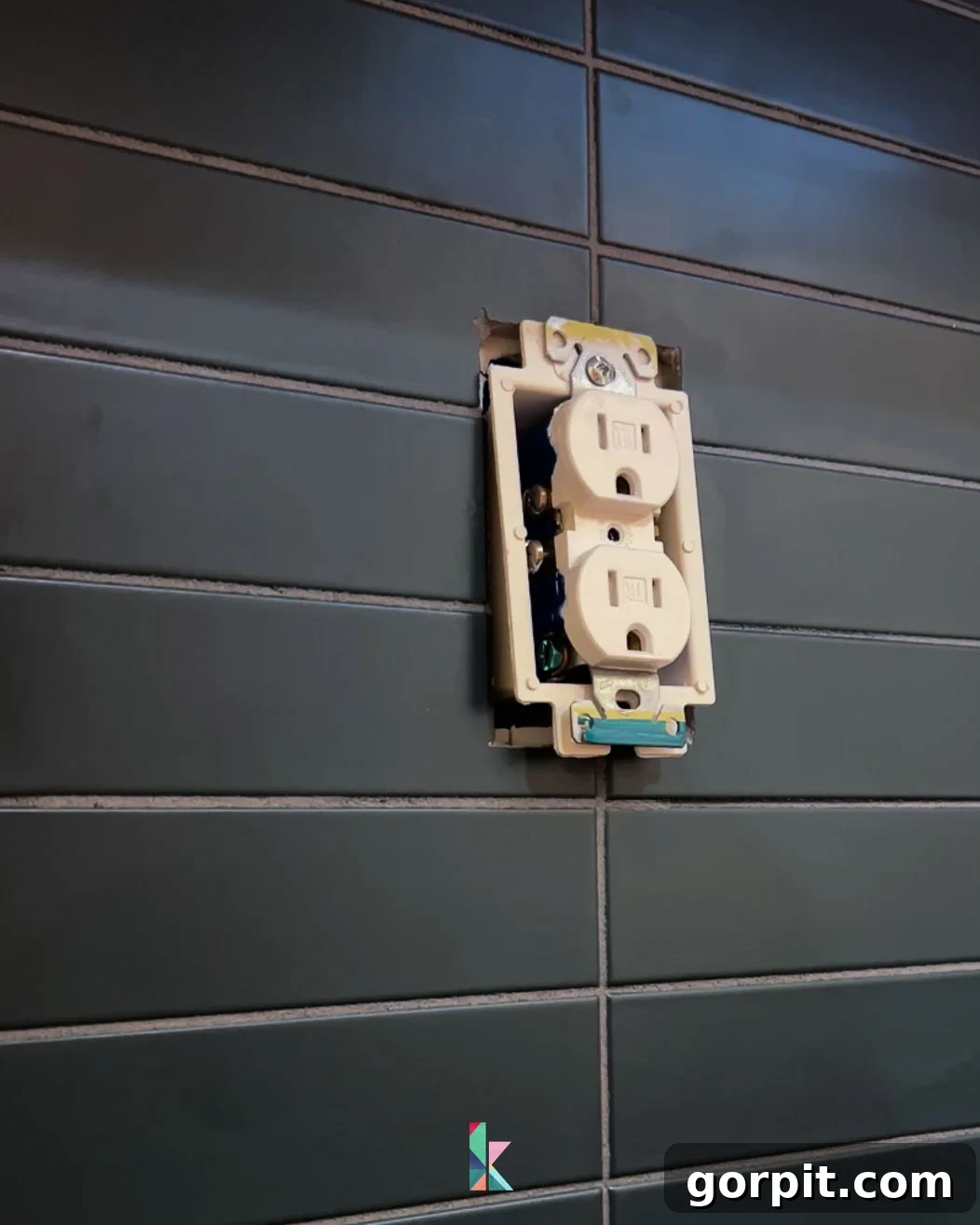 Installing an outlet extender to ensure the electrical outlet sits flush with the newly installed tile backsplash, followed by replacing the cover.