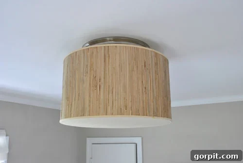 A DIY flush mount light fixture created from a tan drum lampshade, featuring a fabric bottom for a finished and diffused light effect.