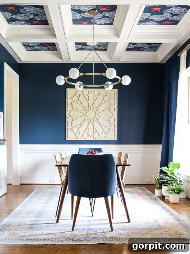 A dining room painted with Sherwin Williams Gale Force navy blue, featuring white wainscoting, a wood floor, and a minimalist dining table and chairs, exuding elegance.