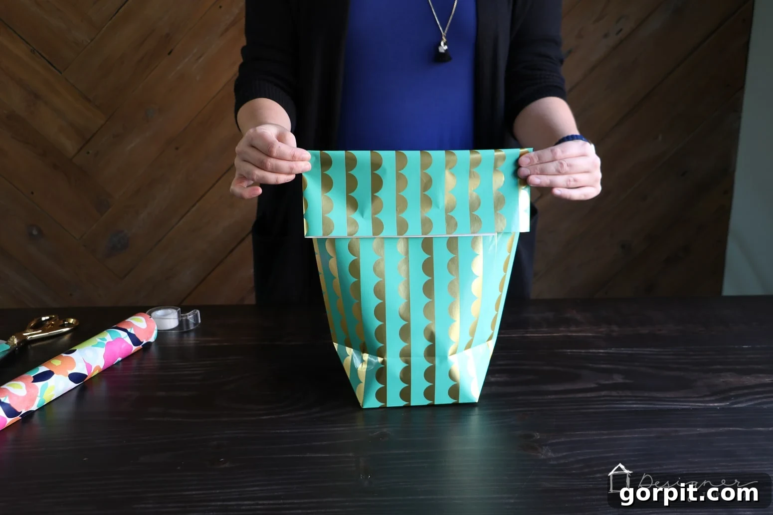 Folding the top flap of the DIY gift bag and punching holes for the ribbon handles to be inserted.