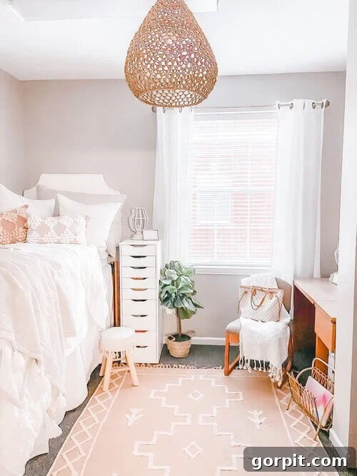 Sophisticated neutrals turn this dorm room into a peach-toned home and works well with the standard wood furniture. These dorm room ideas include a tear-drop hanging light, sheer white curtains, a nightstand with nine drawers, and a high twin bed.