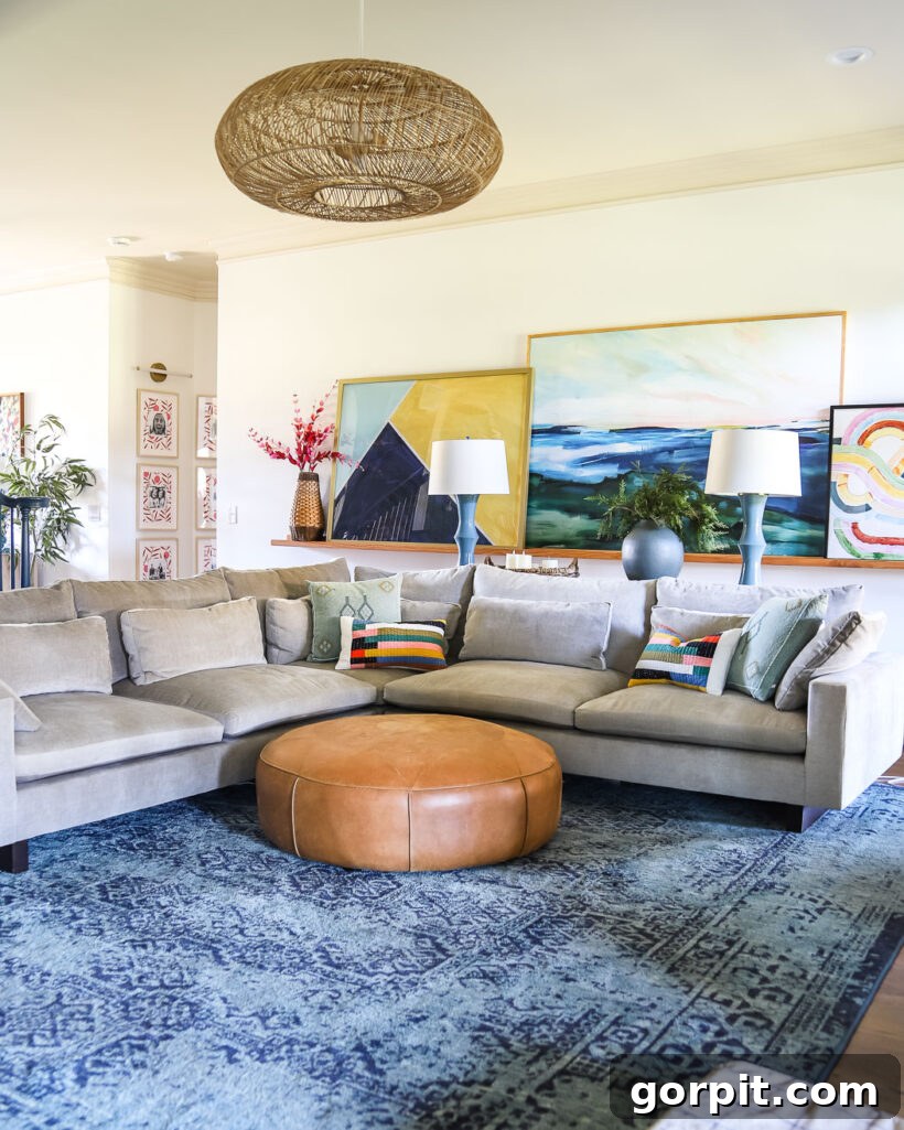 colorful living room with large art, round leather ottoman and large sectional sofa on large blue area rug