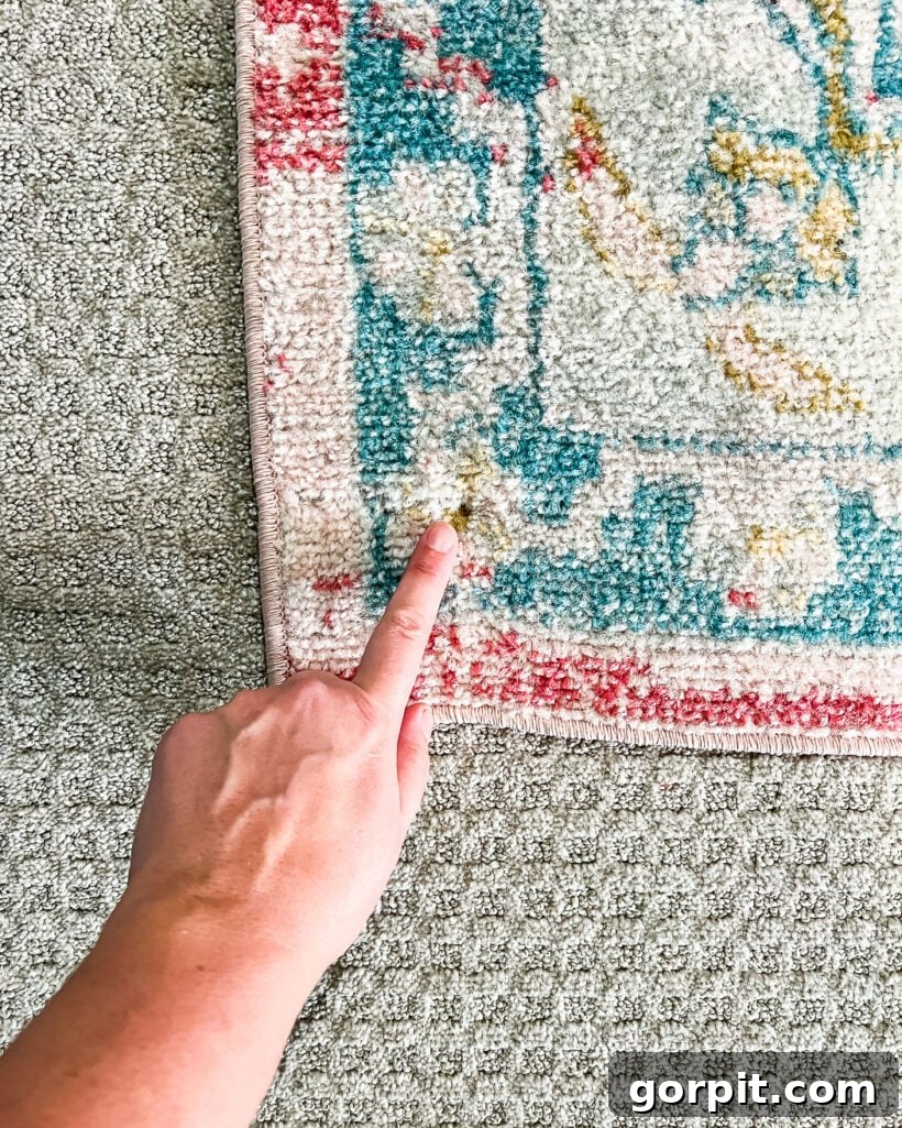 screw in corner of area rug over carpet to keep it in place