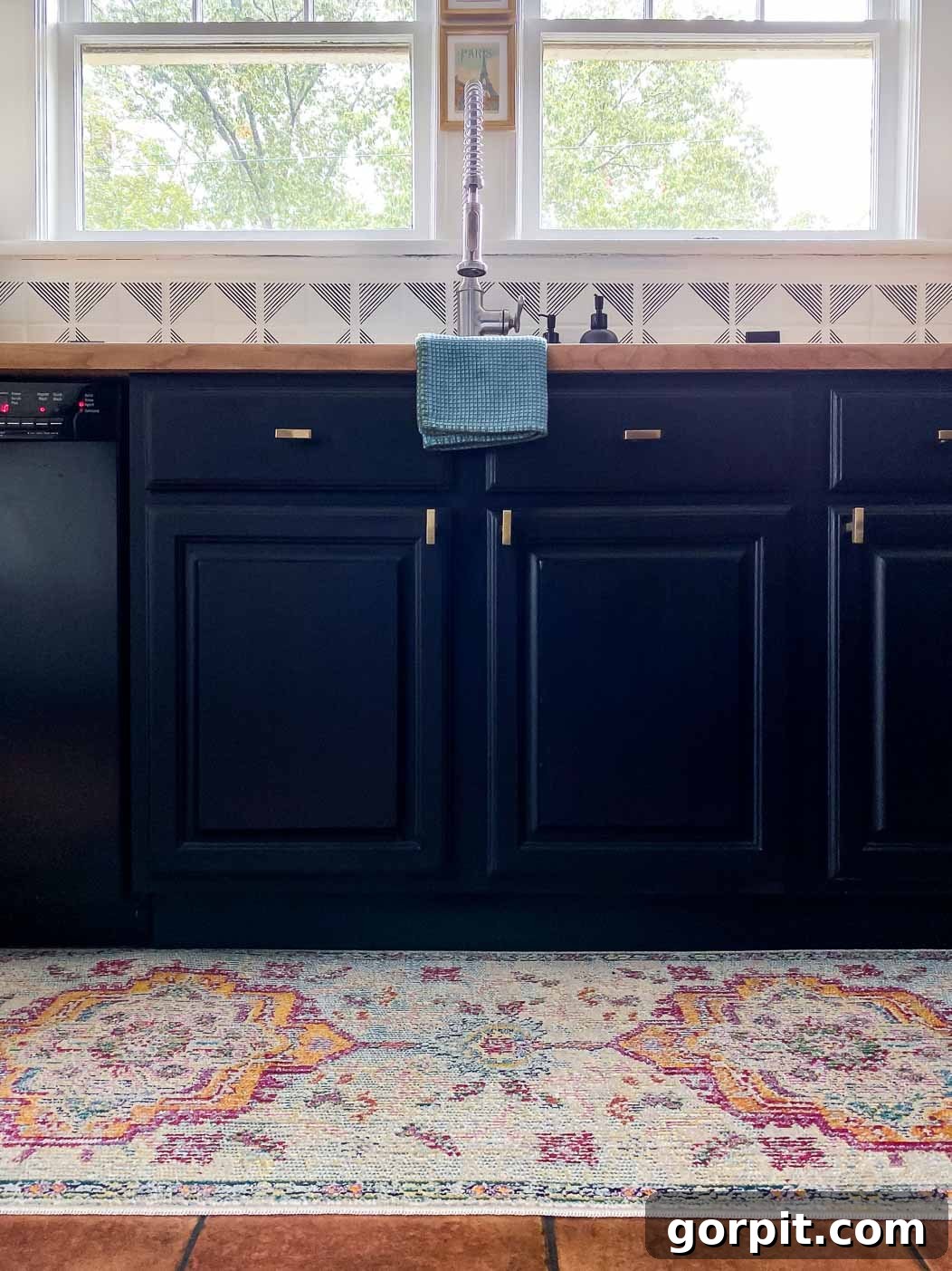 Elevate Your Kitchen Runner Style 2 A colorful medallion kitchen rug runner in front of a sink with deep blue cabinets.