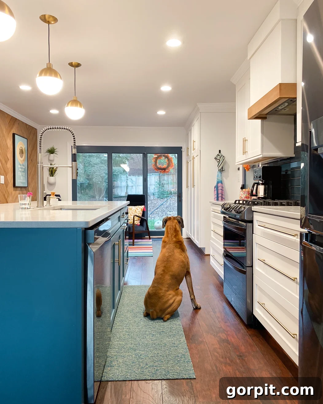 Elevate Your Kitchen Runner Style 6 A Chiliewich woven vinyl kitchen rug runner in colorful kitchen with a bright blue center island. A dog sits on the runner looking out sliding glass doors.