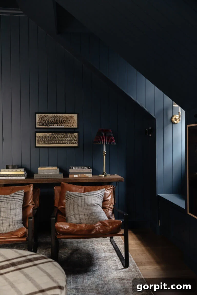 Elevate Your Interiors Innovative Accent Wall Designs 15 A dark attic bonus room has navy shiplap accent walls in the living space along with leather chairs and a slim table, creating a cozy and stylish retreat.