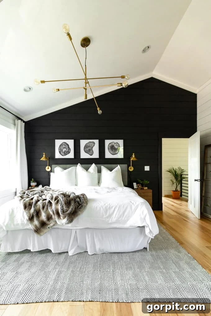 Elevate Your Interiors Innovative Accent Wall Designs 3 A high-ceiling bedroom with a white bed has a black plank accent wall behind it, offering a bold and sophisticated design choice.