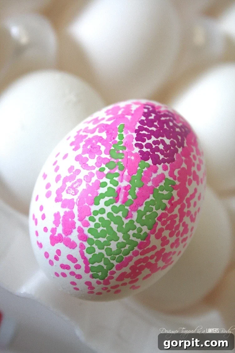 Sharpie Dot Art Easter Eggs 6 A hand gently peeling off a sticker from a fully dried dotted Easter egg, revealing the clean, white negative space.