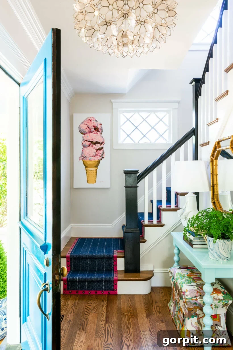 Black newel posts and handrails provide a sharp contrast, complementing a bohemian-style foyer filled with interesting art and decor, in an old home with modern touches.