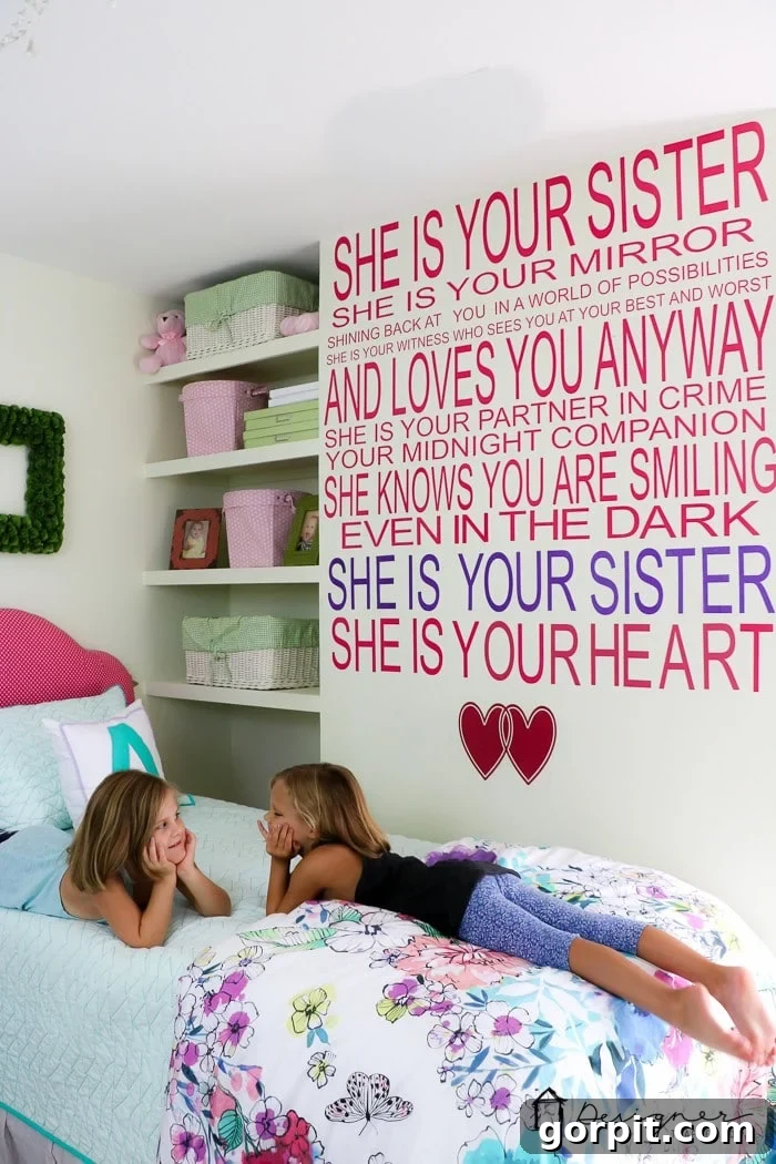 little girls laying on bed with sister quote on wall behind them, showcasing personalized wall decor