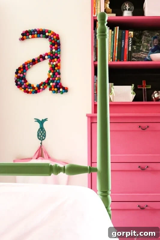 Large colorful DIY wall letter 'A' hanging prominently in a charming pink and green girl's bedroom.