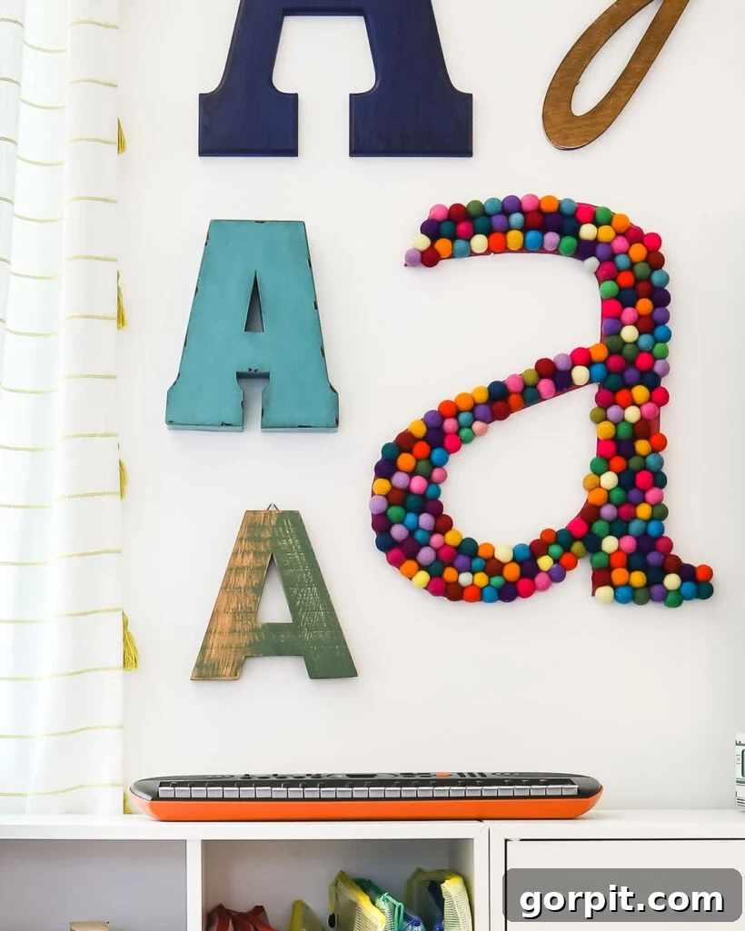 Large DIY wall letter made with an array of colorful felt balls, adding texture and cheer.