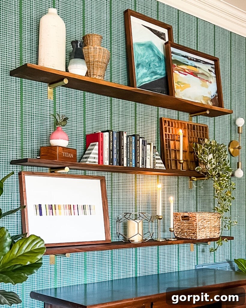 DIY wall shelves styled with books and art hanging on a green and white wall