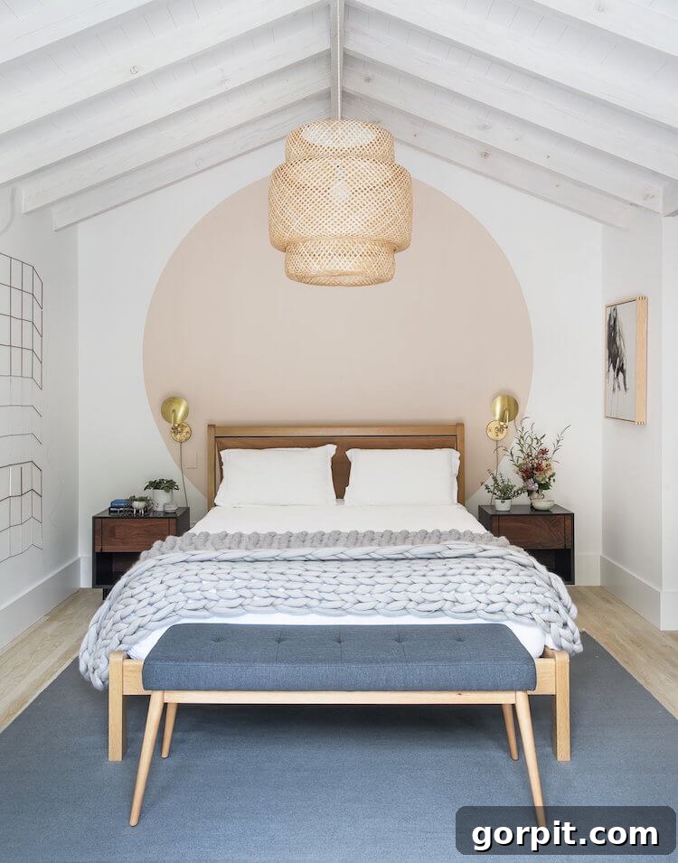 blush circle mural painted behind a pale wood bed in a white room