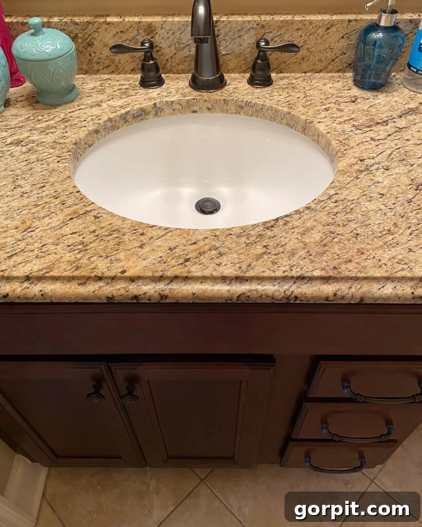 Affordable Bathroom Transformations: Smart DIY Renovation Ideas 5 Outdated brown vanity with brown granite countertop in a bathroom before renovation.
