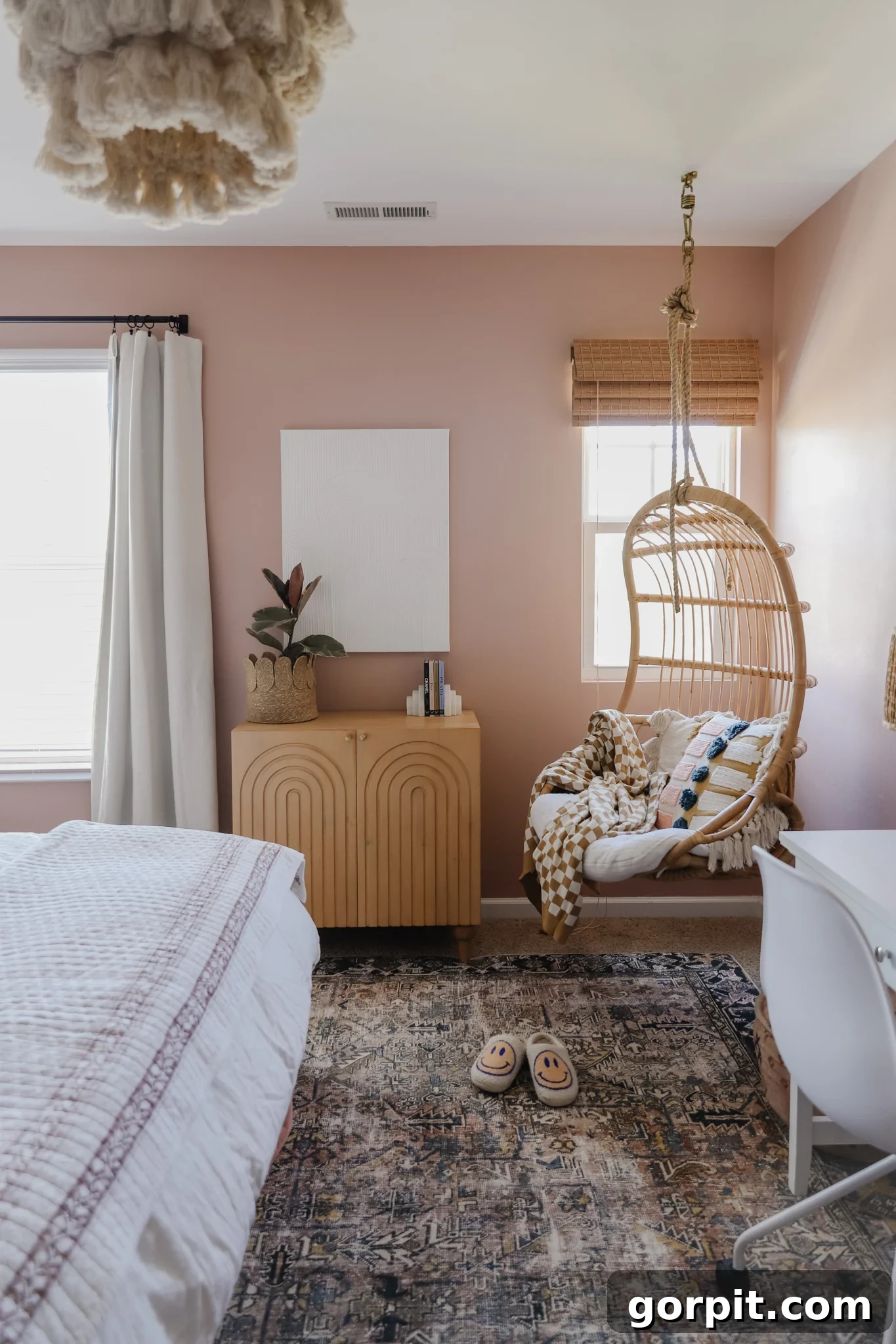 25 Fresh Teen Room Makeover Ideas for Guys and Girls 20 The corner of a teen girl's neutral-colored room features a stylish hanging basket chair, perfectly complementing a cabinet wall unit and a white bed and desk setup. This creates a cozy and functional space for relaxation and study.