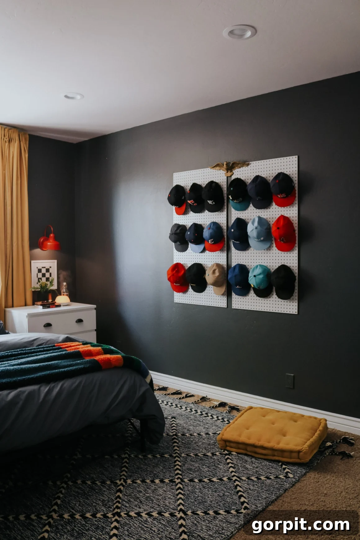25 Fresh Teen Room Makeover Ideas for Guys and Girls 24 Baseball hats are neatly hung on a pegboard, serving as distinctive wall art against a dark wall. A crisp white nightstand sits cozily in the corner of this teen boy's room, adding both functionality and personal style.