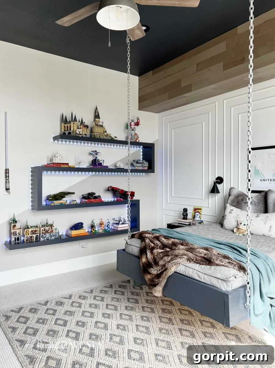 25 Fresh Teen Room Makeover Ideas for Guys and Girls 26 A unique bed, suspended by sturdy white chains, hovers gracefully over a soft grey rug. Floating zigzag shelves, illuminated by subtle lighting, proudly display creative LEGO builds, adding a playful yet sophisticated touch to the room.