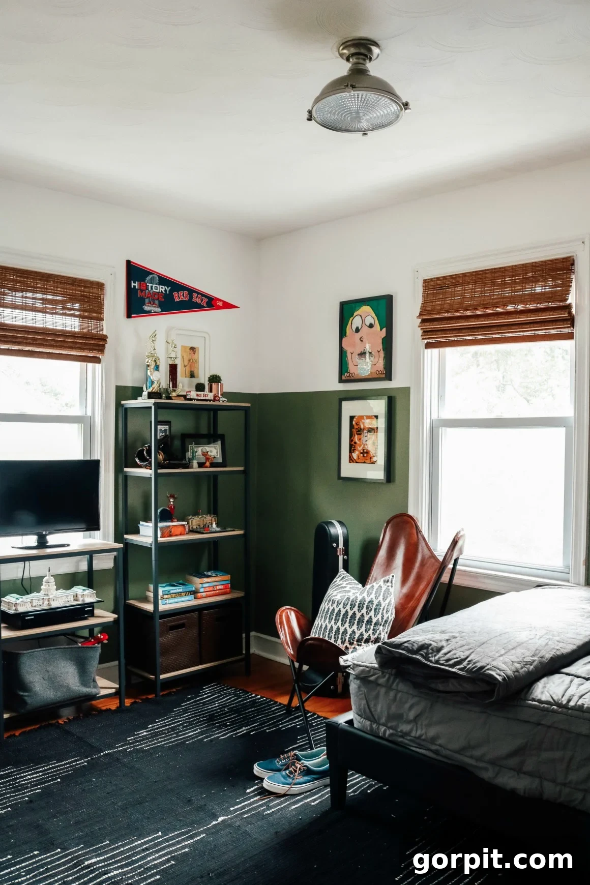 25 Fresh Teen Room Makeover Ideas for Guys and Girls 28 A stylish, dark green teen boy's bedroom features a dedicated gaming shelf integrated with a corner bookcase, creating a sophisticated and functional space for both entertainment and study.