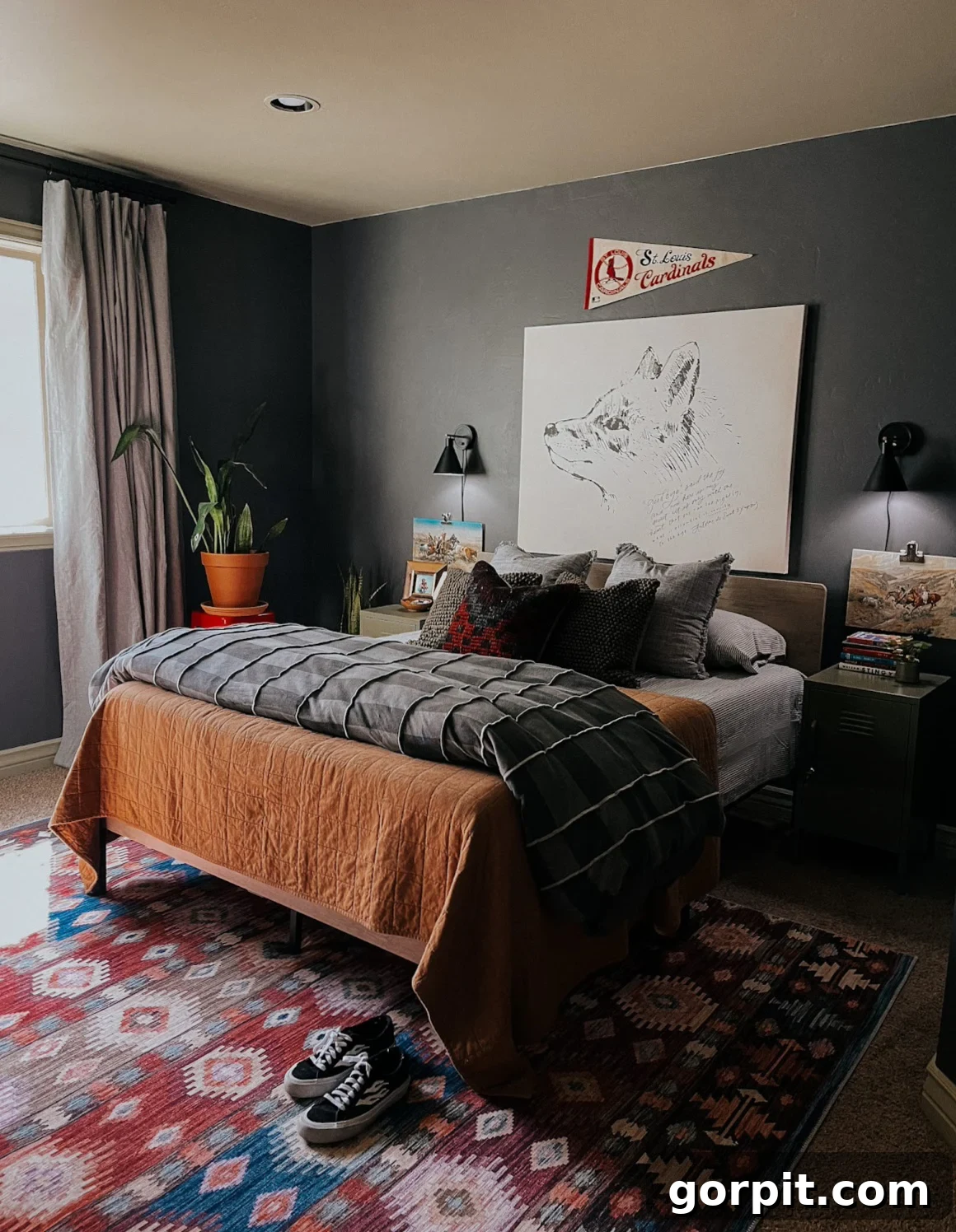 25 Fresh Teen Room Makeover Ideas for Guys and Girls 29 A dark grey boy's bedroom exudes comfort with its layered, textured bedding and a vibrant potted plant. A large, striking line drawing of a dog proudly hangs above the bed, adding a personal and artistic touch.