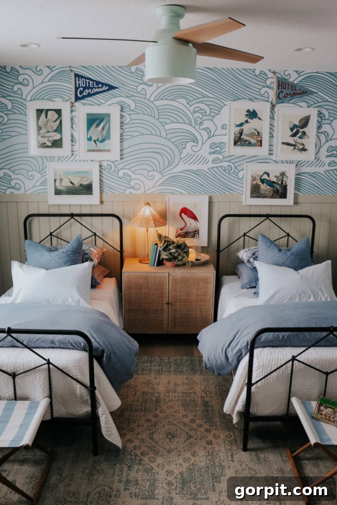blue wave wallpaper with metal beds with blue and white bedding and bird prints over beds