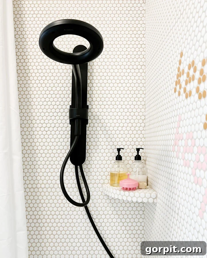New black shower head in a girl's bathroom, highlighting penny tile installed over outdated tiles