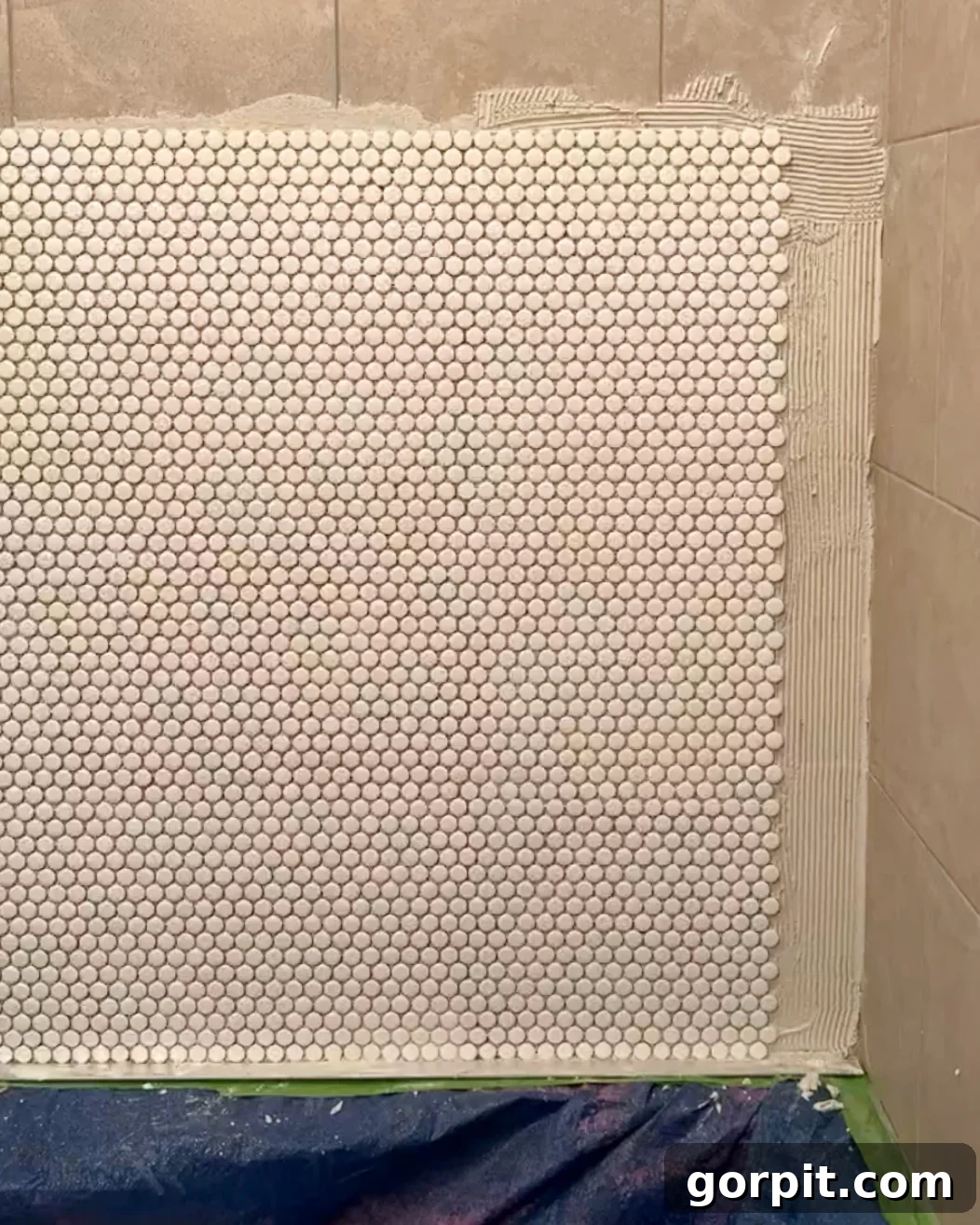 Penny tiles being installed in a shower over existing tiles, demonstrating the tiling process