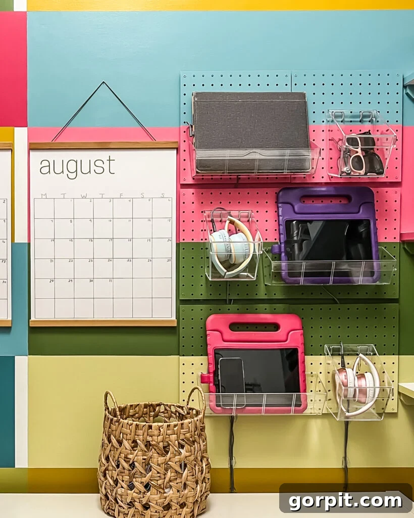 DIY vertical family charging station made from white pegboard with clear acrylic bins holding electronic devices like phones and tablets