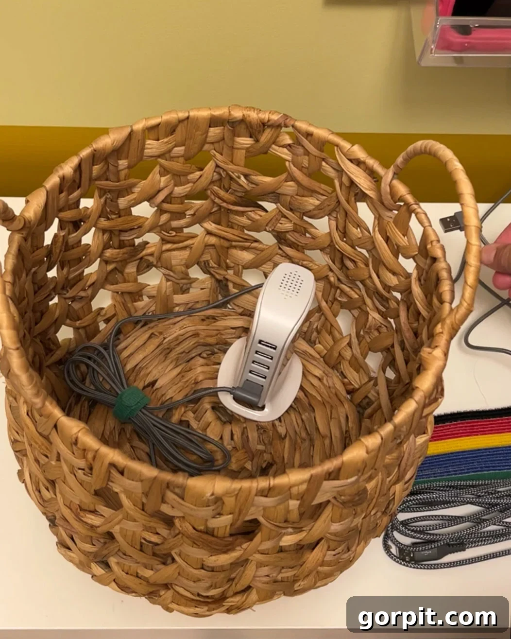 Close-up of a USB charging tower placed inside a woven basket on the pegboard, with cords emerging for devices