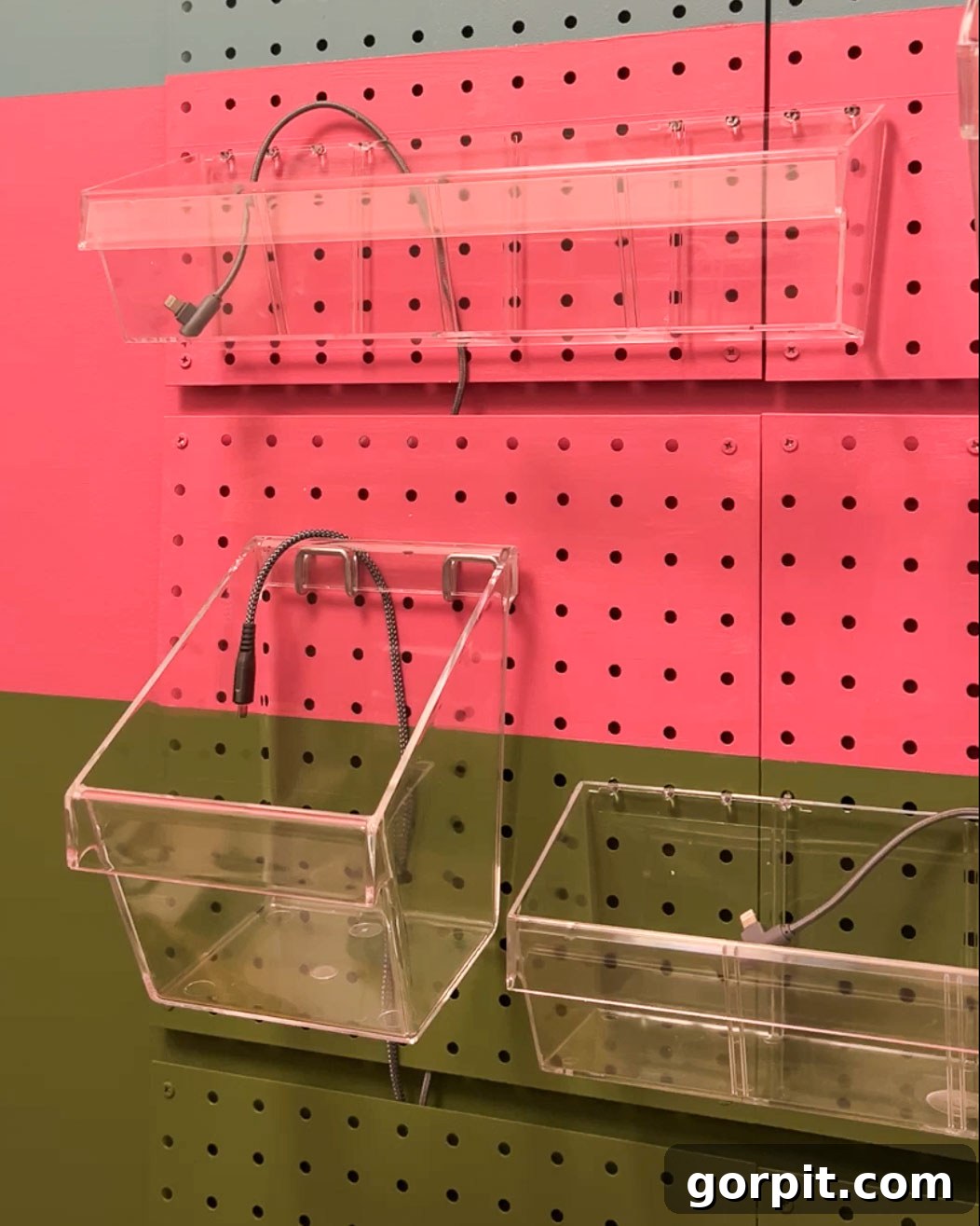 Detailed view of charging cords neatly routed behind the pegboard and pulled through gaps to individual device bins