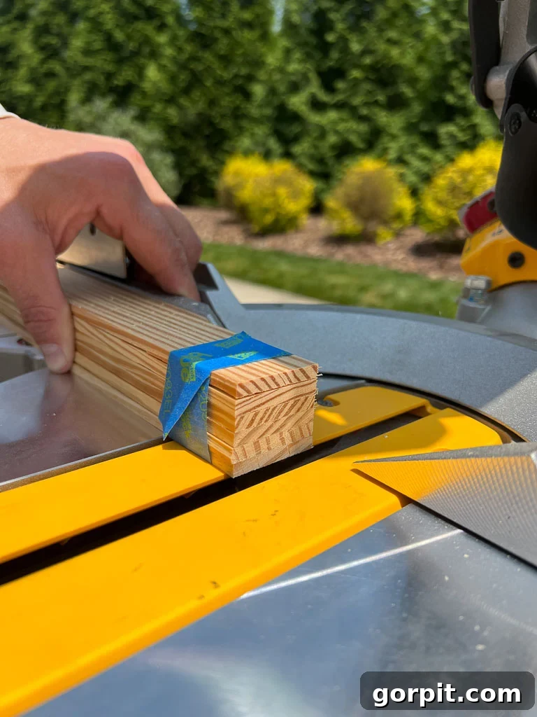 Cutting lattice strips to length using a compound miter saw, with painter's tape securing the wood for precision.