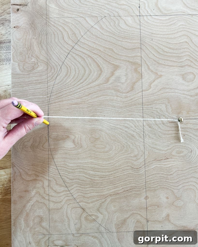 drawing arch shape onto plywood with nail and string attached to pencil