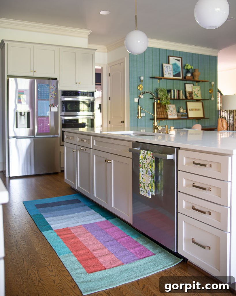 Our Kitchen Renovation Reveal A Perfect Blend of Neutral and Color 7 Photo of the kitchen featuring cabinets painted in Sherwin Williams Accessible Beige, openly flowing into the great room adorned with colorful decor and vibrant green and blue accents.