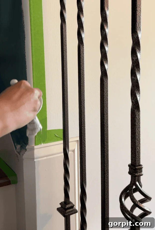 Image of a hand holding a paintbrush, meticulously painting along the edge of painter's tape with the existing wall color to effectively seal it and prevent the new, contrasting paint from bleeding underneath.