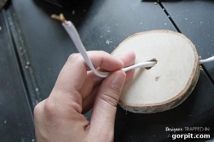 Threading the Lamp Cord Through the Drilled Tunnel in the Wood Slice Base