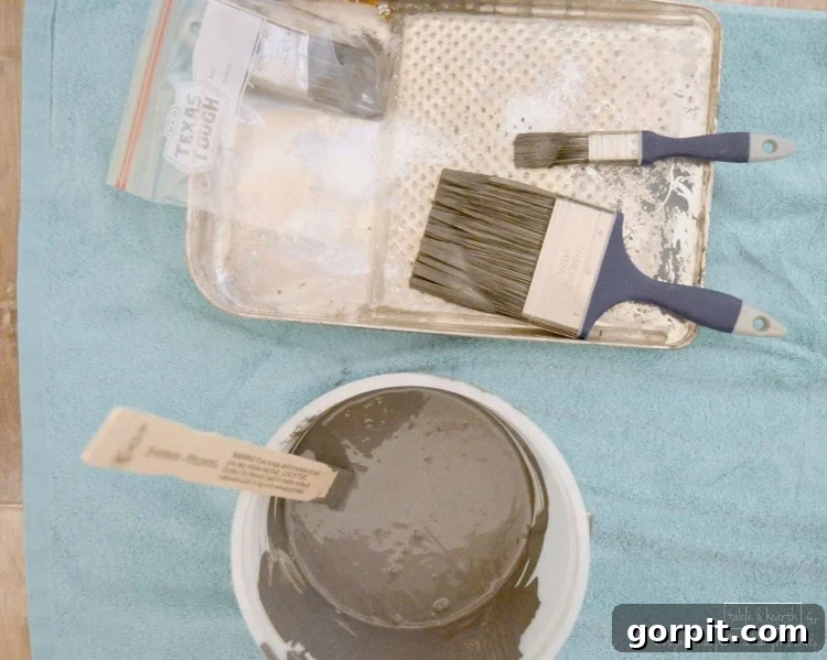 Painting a DIY wood plank wall with a brush, showing tools and technique