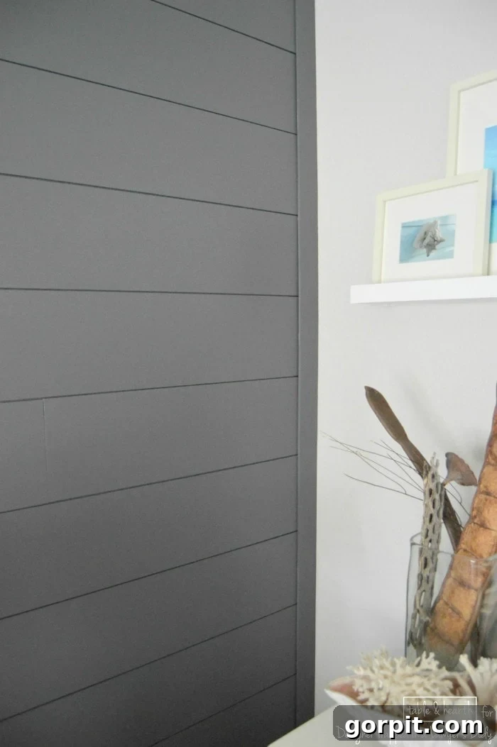 Beautiful dark grey DIY wood plank accent wall in a coastal-themed bedroom