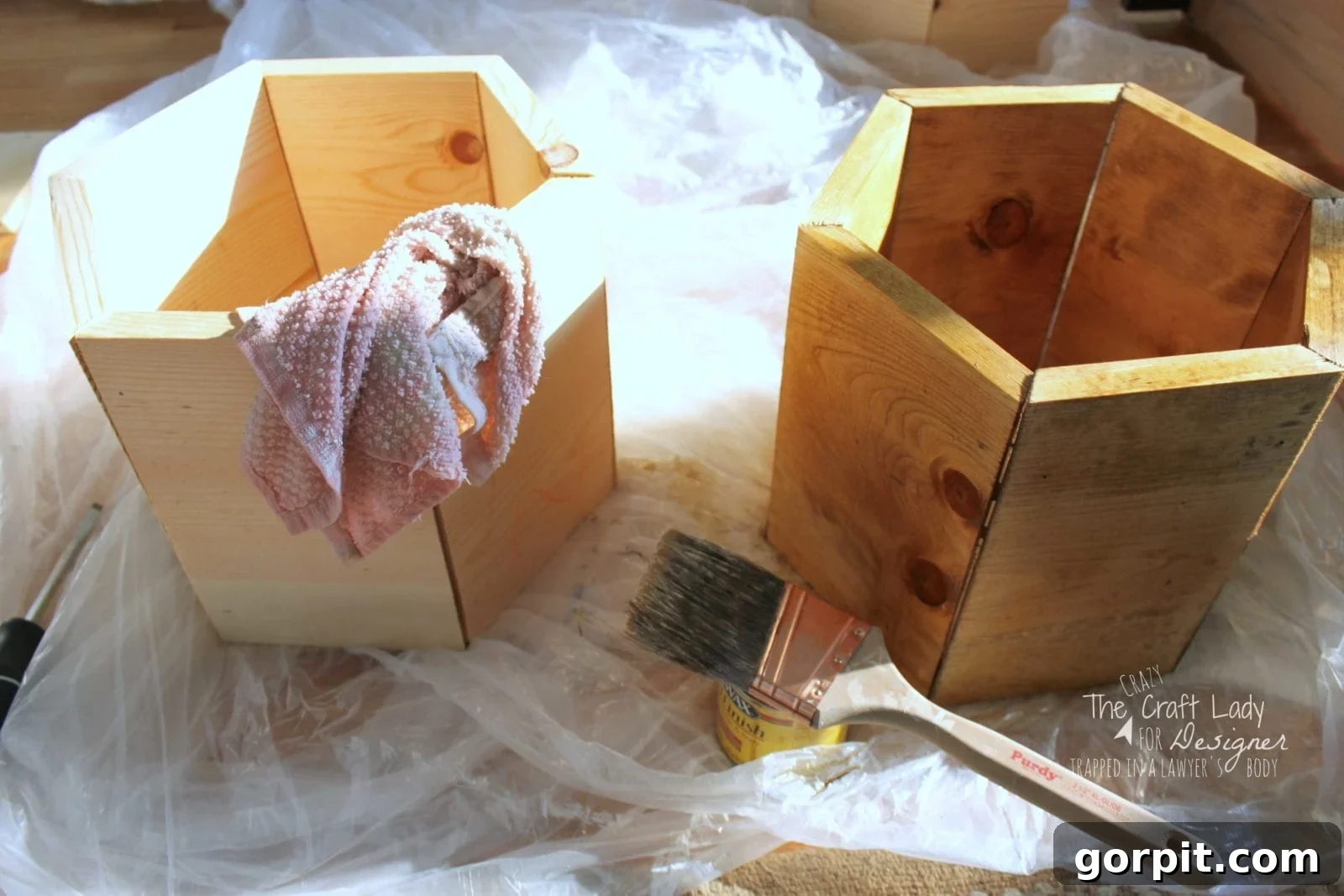 Honeycomb Shoe Rack DIY 14 Two deep hexagonal shoe cubbies, one stained and one unstained, on a drop cloth next to a small container of stain and a paint brush. These honeycombs-style organizers are used in a DIY shoe rack made from an IKEA Billy bookcase.
