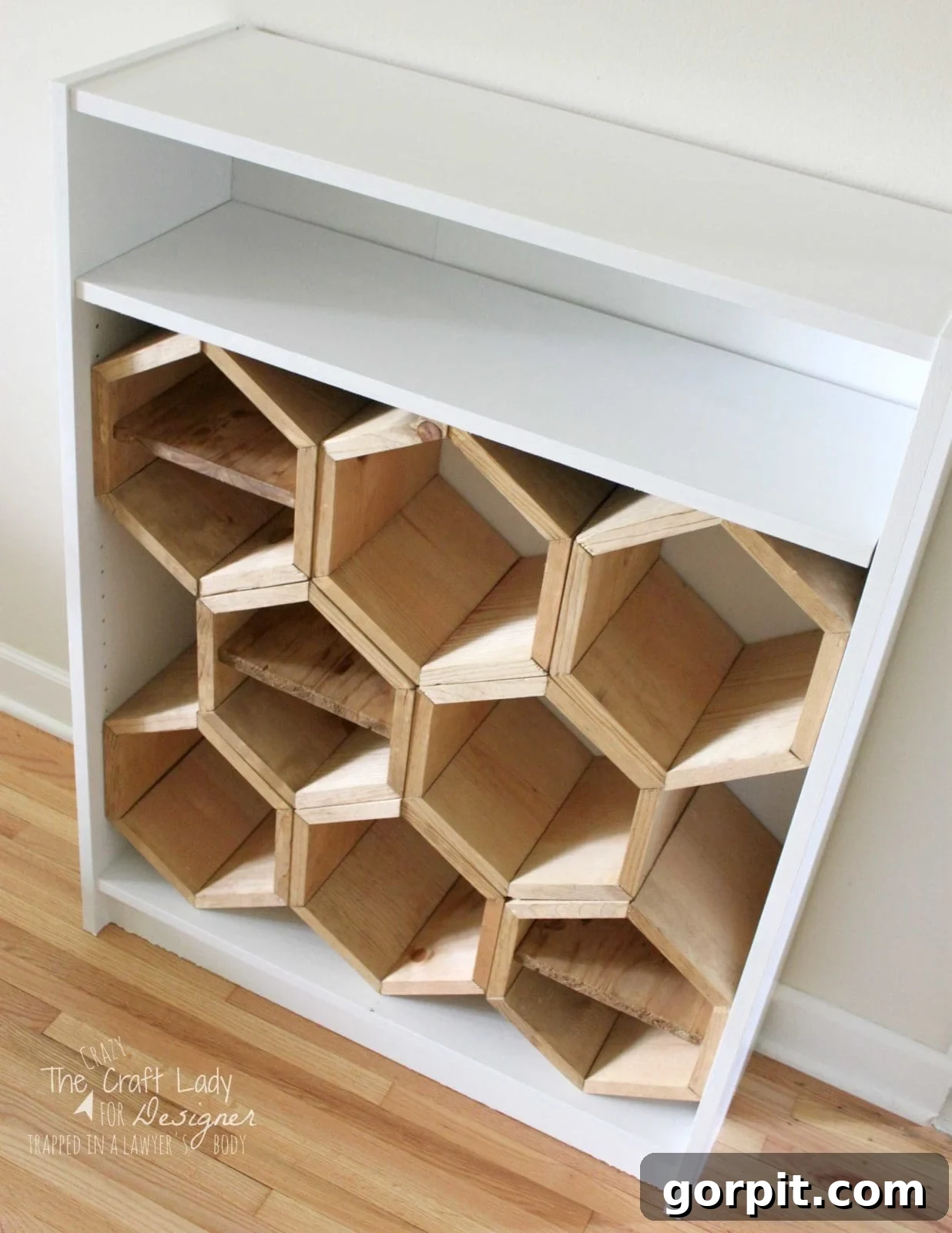 Honeycomb Shoe Rack DIY 17 A white bookshelf with custom honeycomb-style wooden hexagon shoe compartments fitted inside the lower half, with a short white shelf above for additional storage.