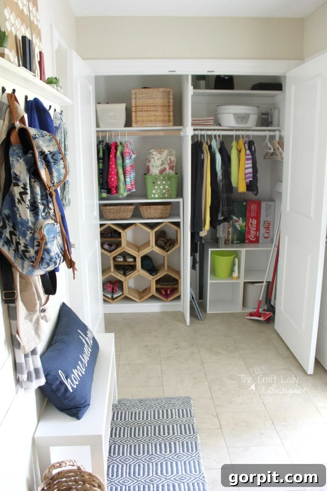 Honeycomb Shoe Rack DIY 18 An organized mudroom and entryway closet open to show hanging clothes, woven baskets, a DIY shoe rack made of hexagon wood compartments, storage bins, and a bench with pillows and backpacks.