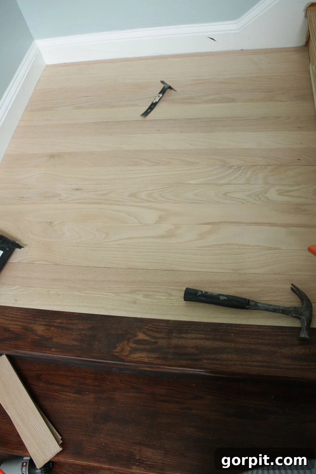 Installing hardwood flooring on a stair landing to match the newly installed stair treads.