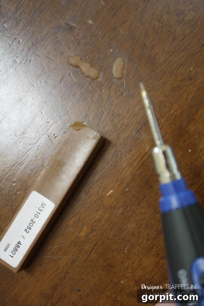 Using a Quick Fill Burn-In Stick to repair a deep gouge in a wooden table.